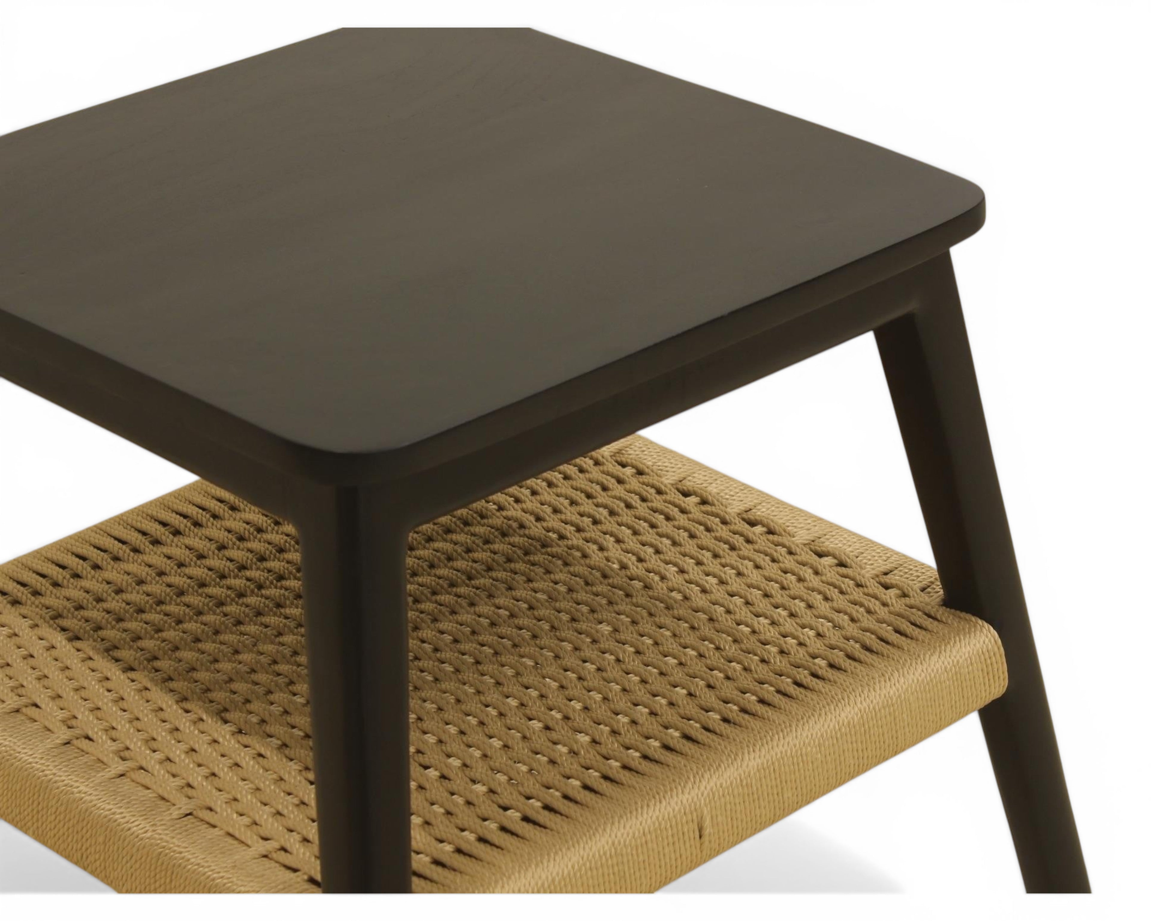 Nakoda Homes black wooden side table with natural woven rattan shelf. Modern accent table.