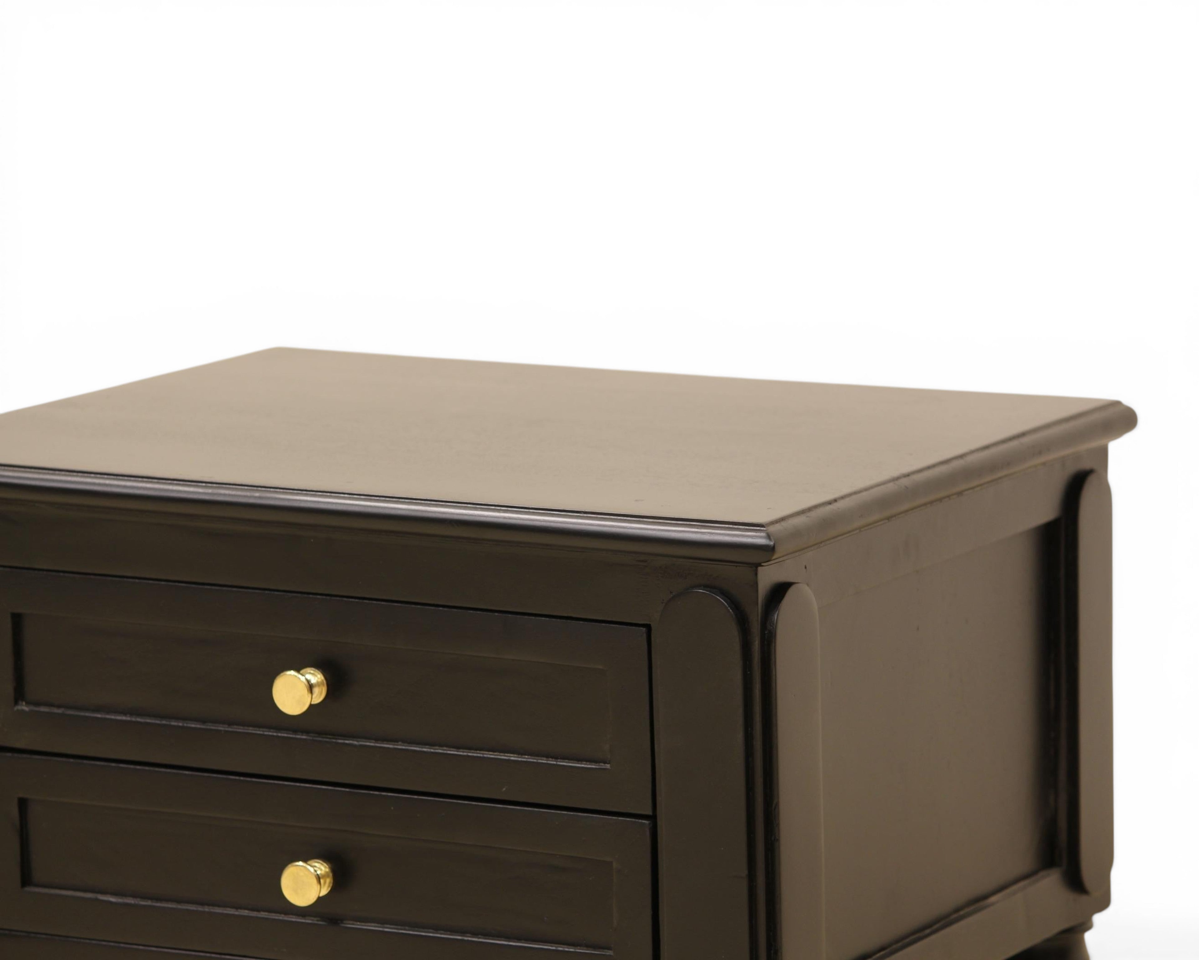 Nakoda Homes black wooden nightstand with two drawers, gold hardware, and decorative legs. Offers classic bedroom storage.