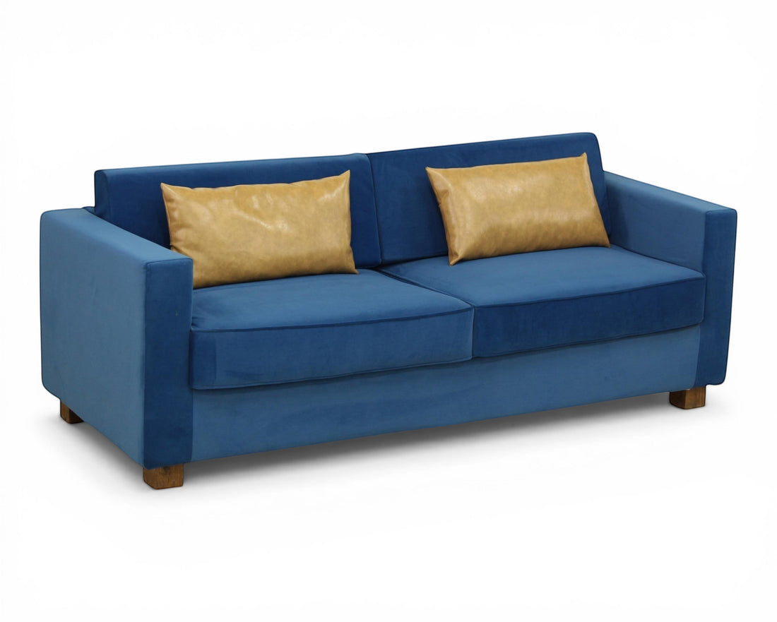 Nakoda Homes blue velvet sofa with tan accent pillows, modern design, plush upholstery, and clean lines.