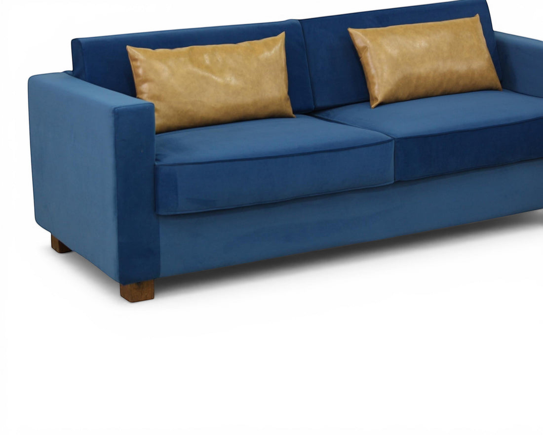 Nakoda Homes blue velvet sofa with tan accent pillows, modern design, plush upholstery, and clean lines.