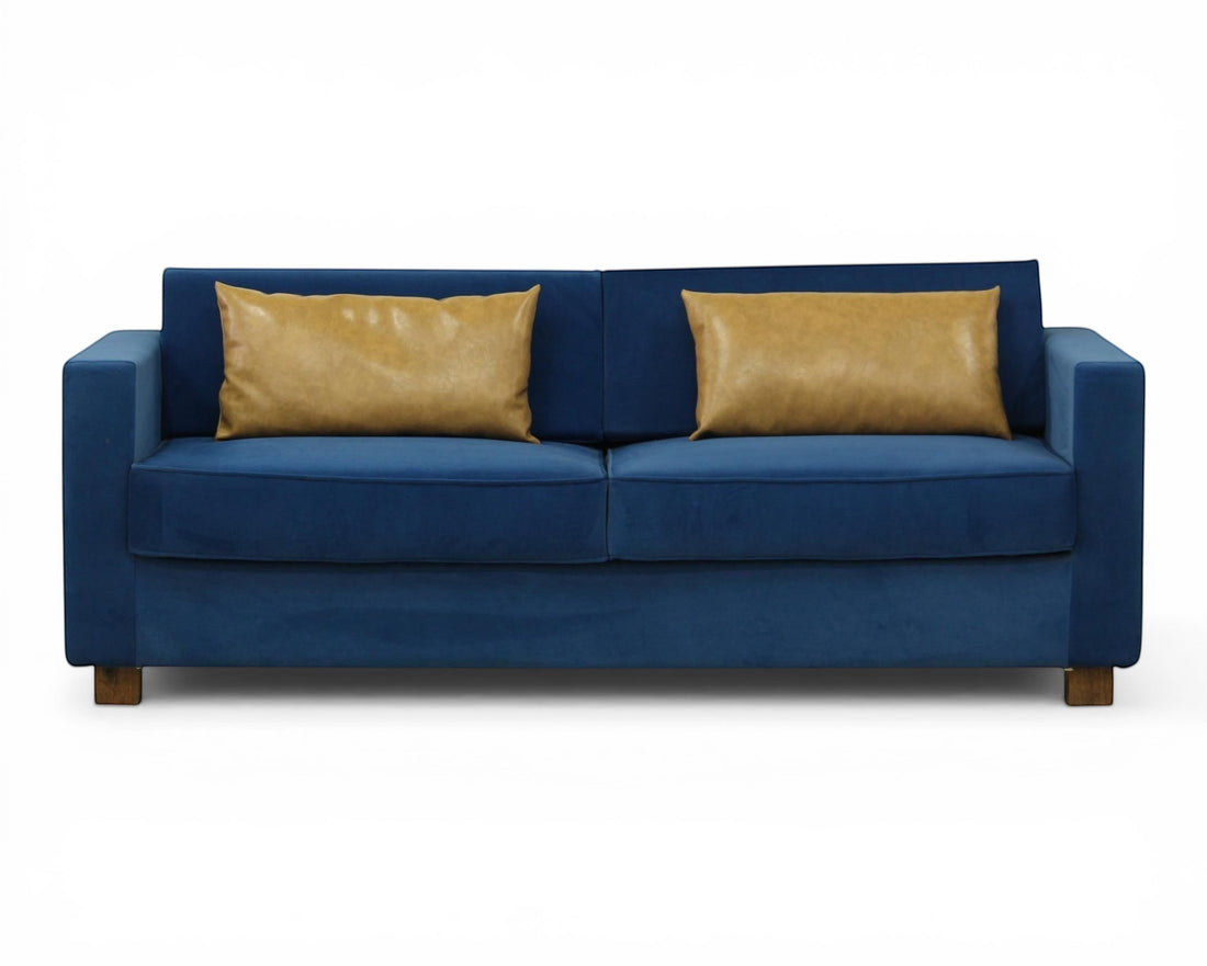 Nakoda Homes blue velvet sofa with two tan accent pillows, modern design, plush upholstery.
