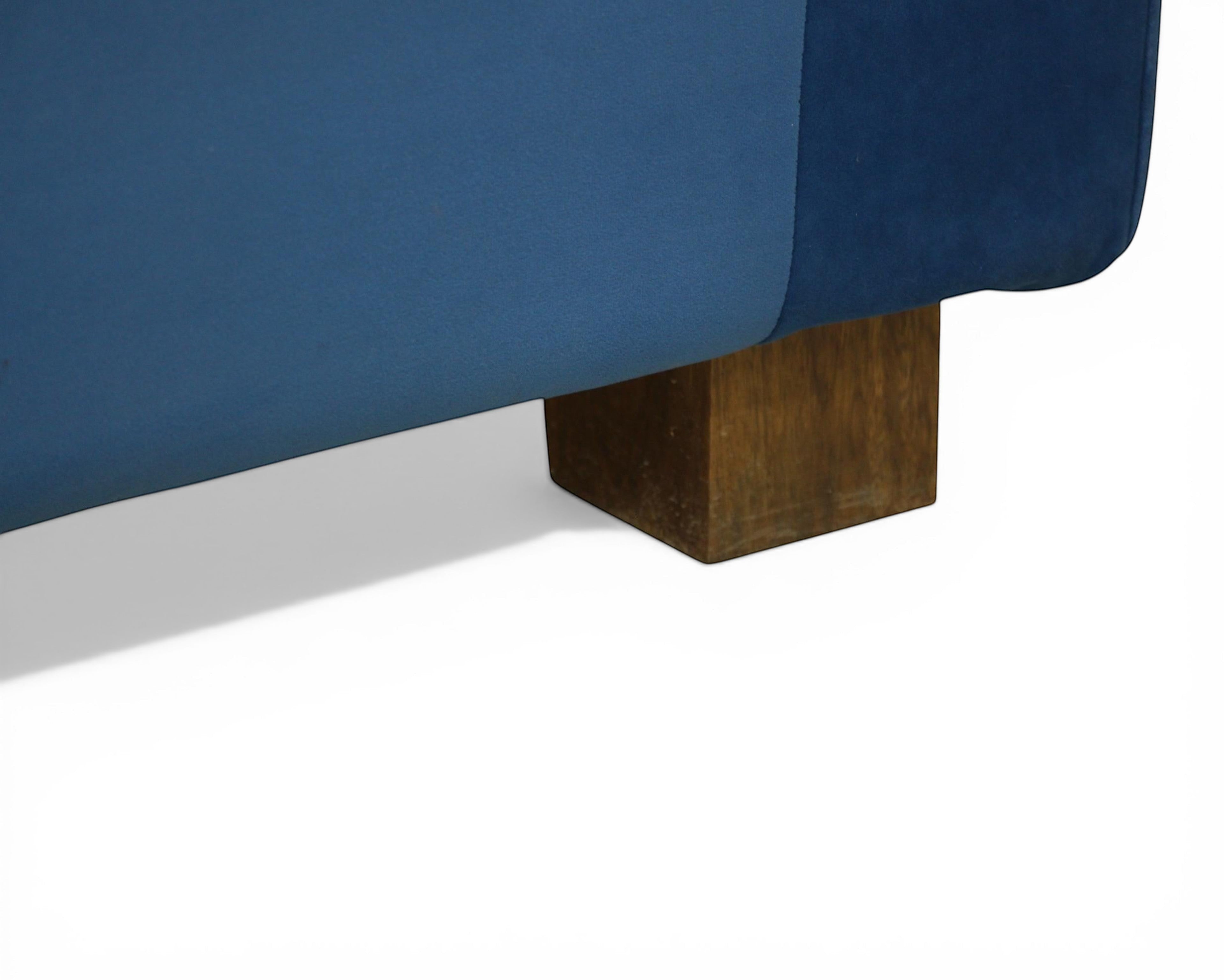 Nakoda Homes blue velvet sofa with wooden legs and tan accent pillows. Modern design.