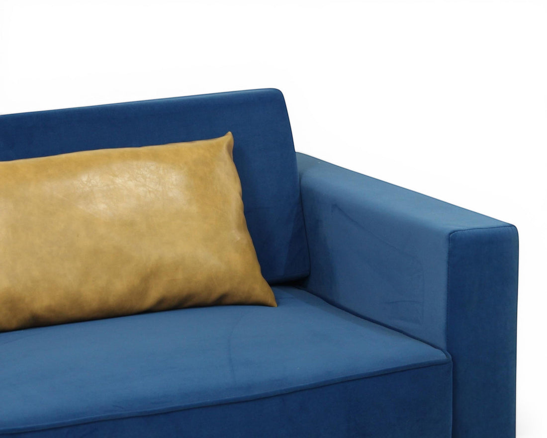 Nakoda Homes blue velvet sofa with tan accent pillow, modern design, plush upholstery.