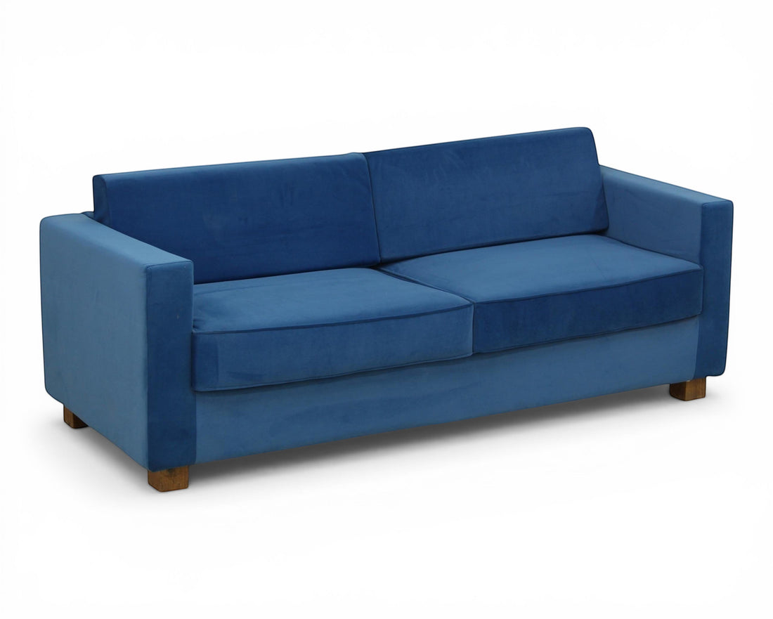 Nakoda Homes blue velvet sofa with clean lines and modern silhouette. Plush upholstery and wooden legs.