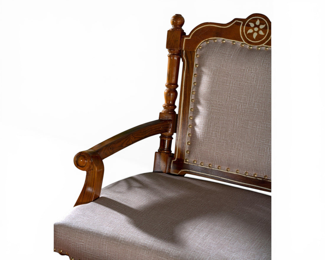 Nakoda Homes ornate carved wood armchair with neutral upholstered seat and back, decorative nailhead trim.