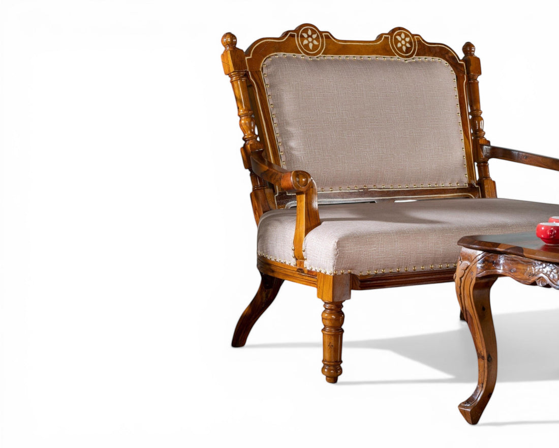 Nakoda Homes ornate carved wood armchair with neutral upholstered seat and back, decorative nailhead trim, and curved legs.
