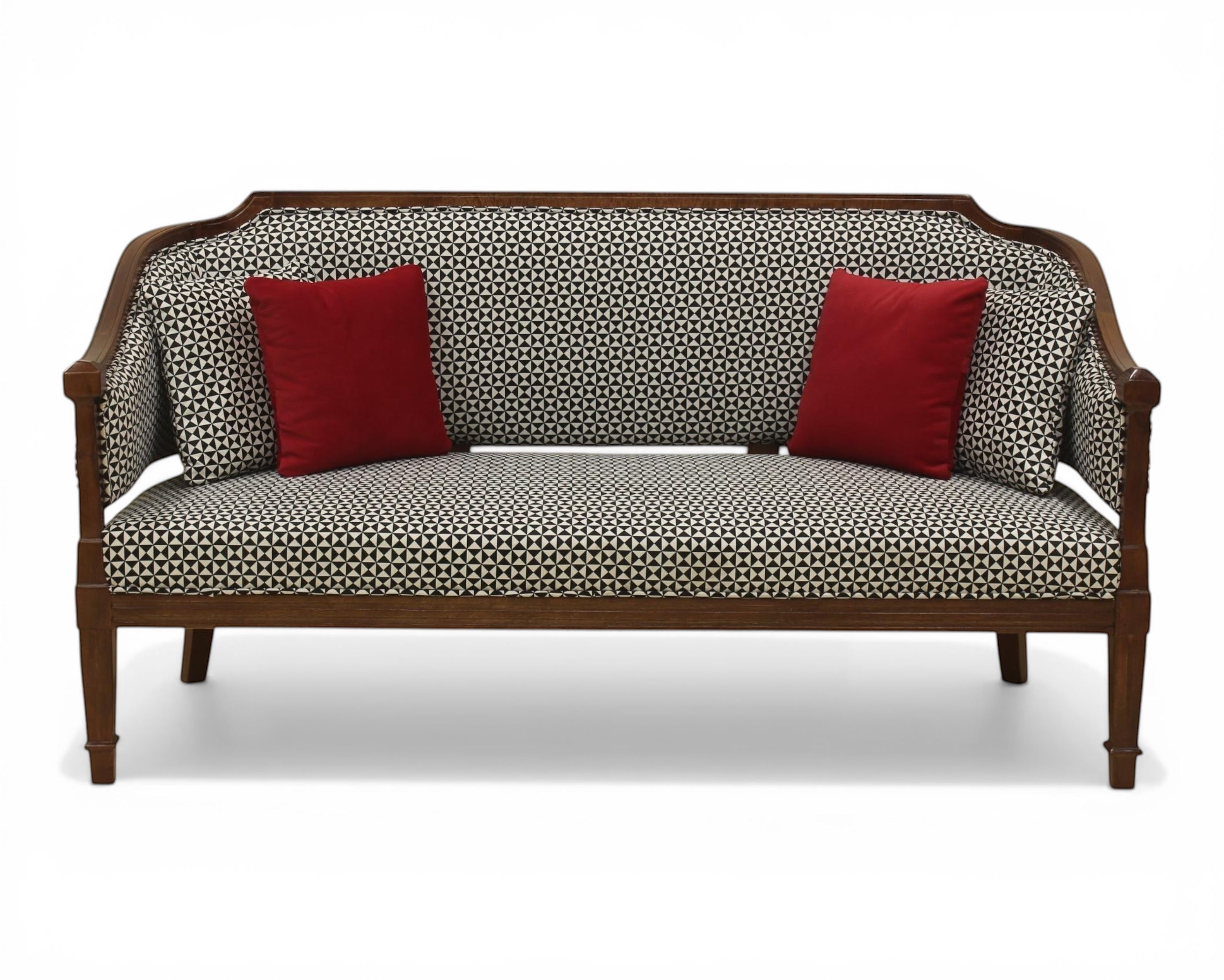 Nakoda Homes classic wooden armchair with red accent pillows and black & white geometric upholstery. Features cane detailing.