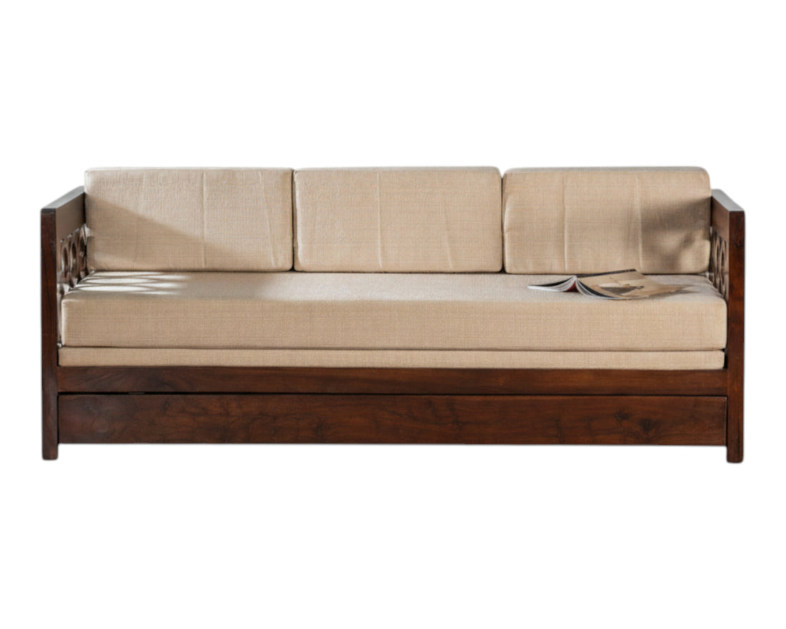 Nakoda Homes dark wood daybed with neutral upholstered seat and intricate armrest detailing. Converts to a bed.