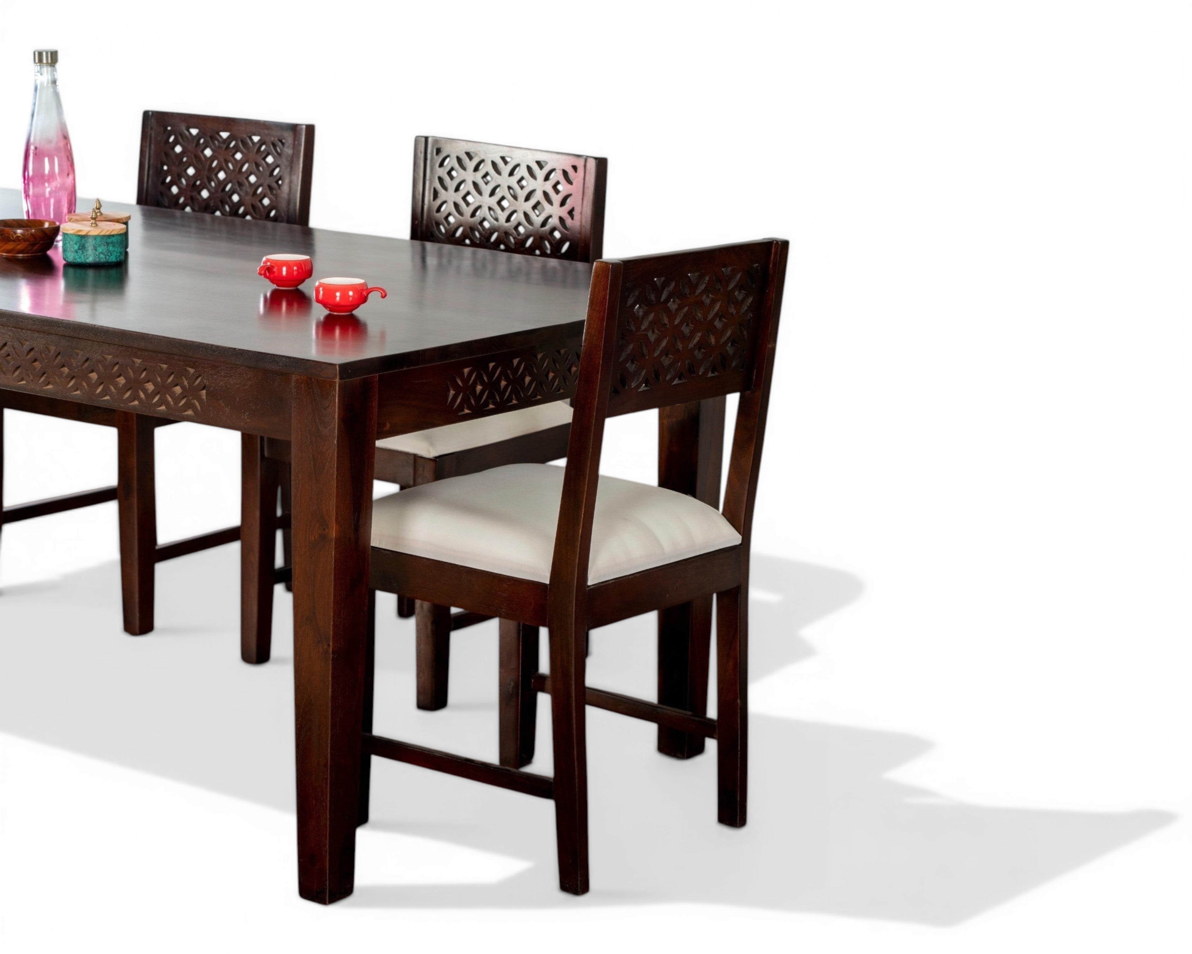 Nakoda Homes dark wood dining set with white upholstered chairs and geometric carvings.