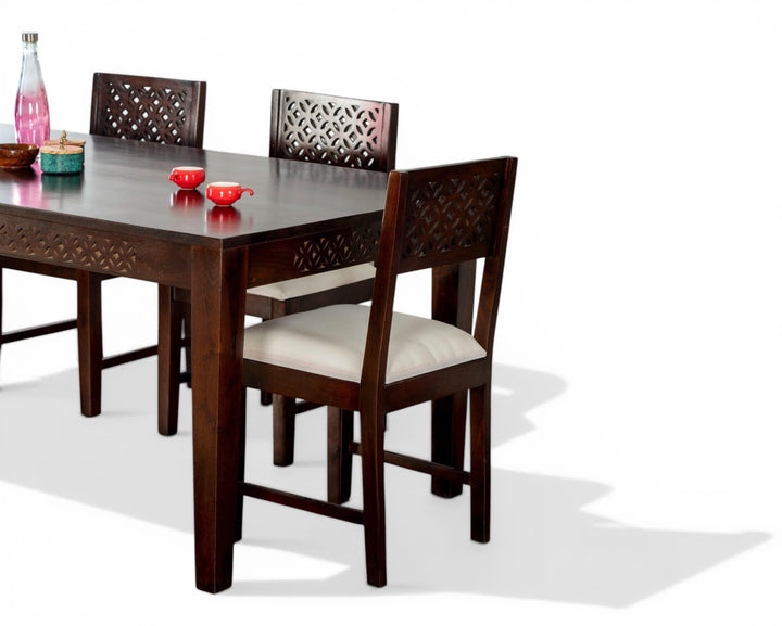Nakoda Homes dark wood dining set with white upholstered chairs and geometric carvings.