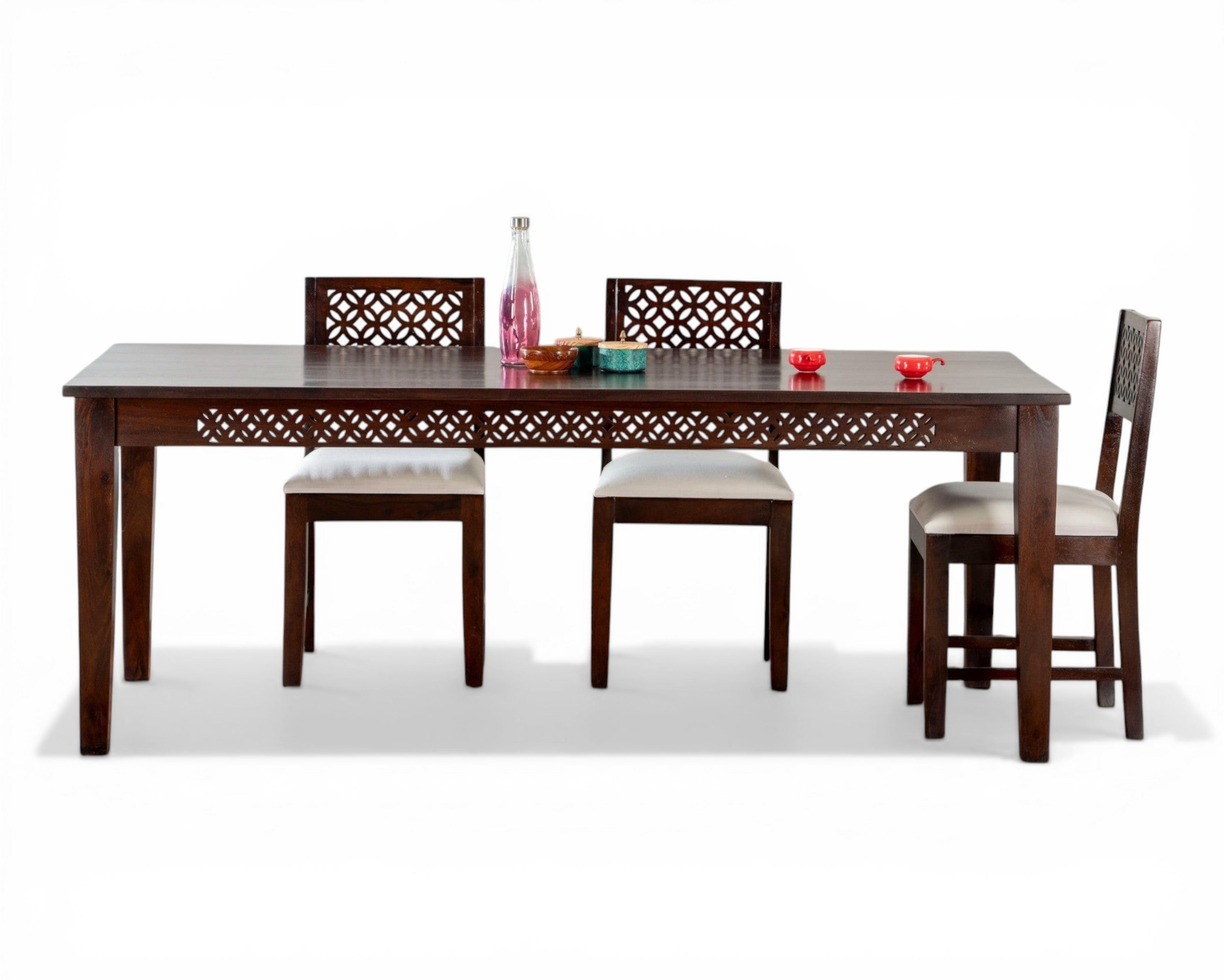 Nakoda Homes dark wood dining set with white upholstered chairs and intricate geometric carvings.