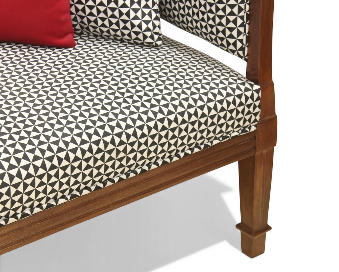 Nakoda Homes armchair with geometric black and white patterned upholstery, wooden frame, and red accent pillow.