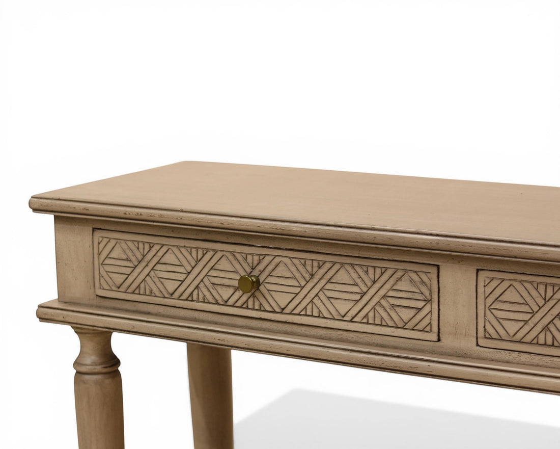 Nakoda Homes distressed grey wood console table with carved geometric drawers and brass knobs.