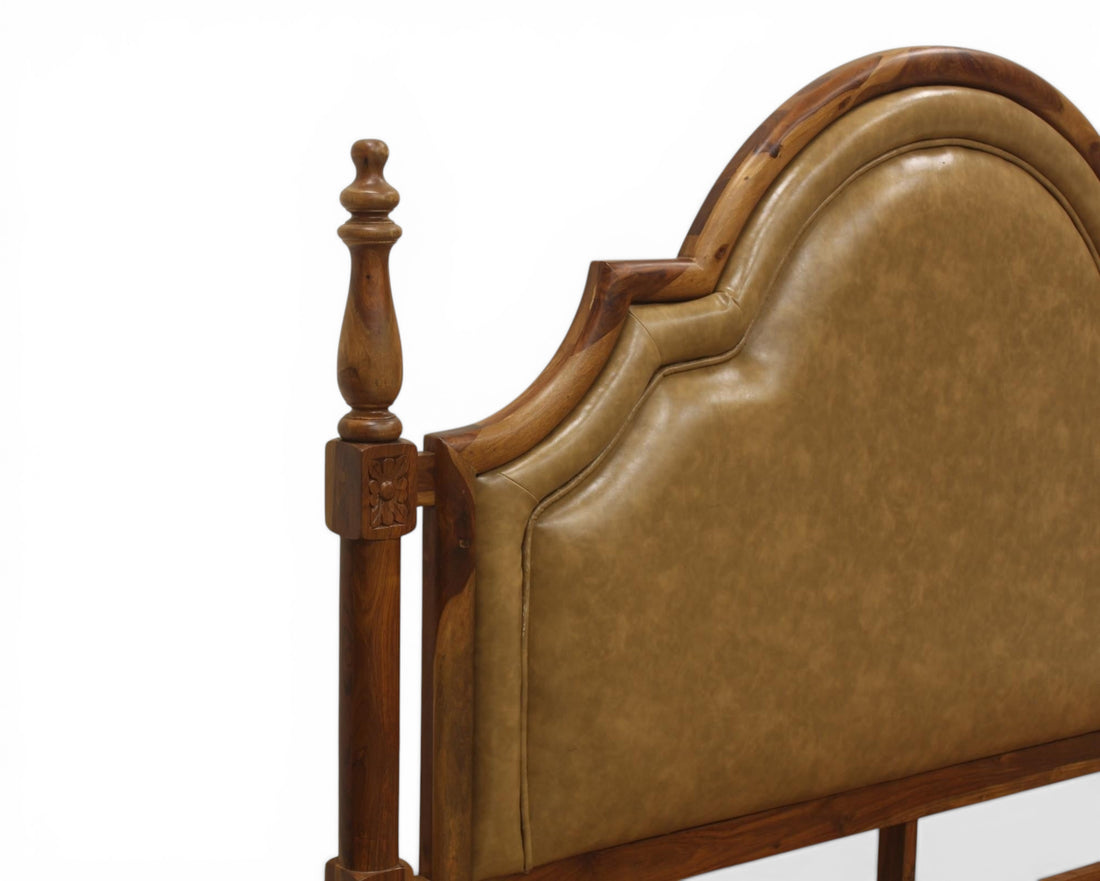 Nakoda Homes ornate wooden bed frame with padded tan leather headboard and carved posts.