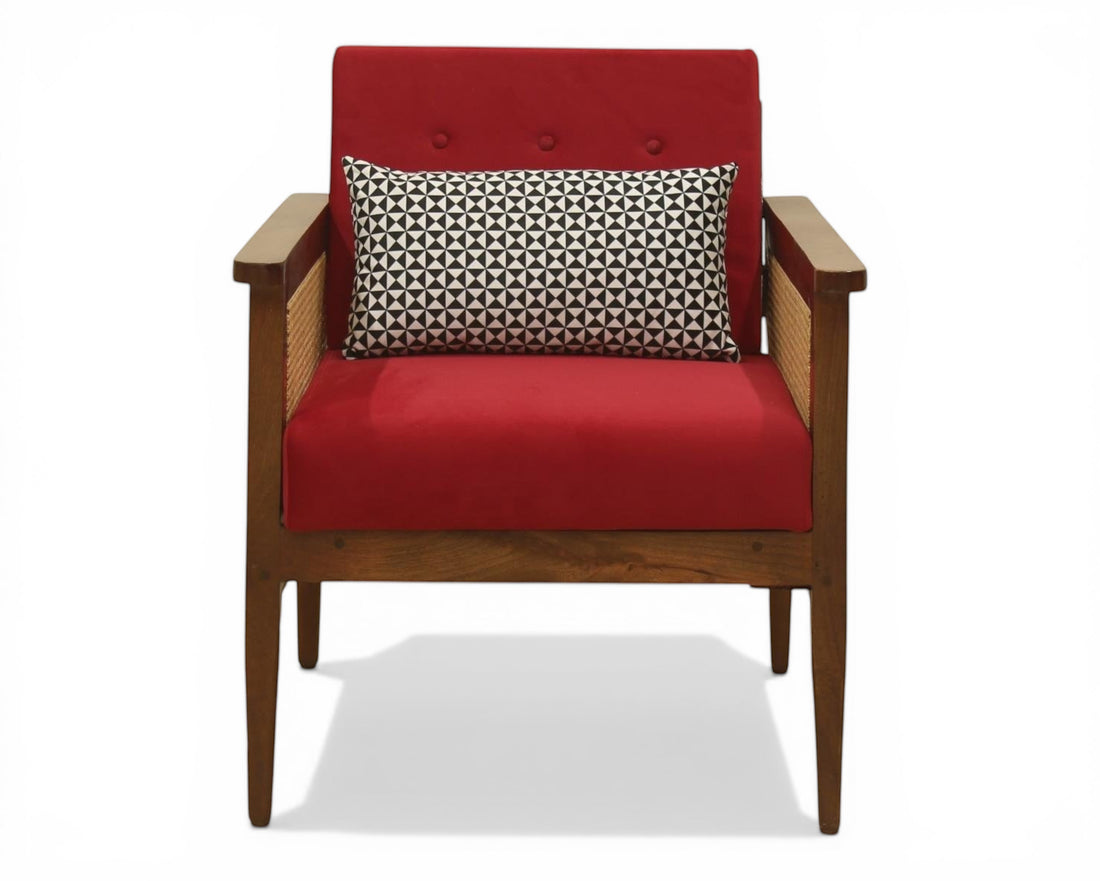 Nakoda Homes red armchair with wooden frame, cane detailing, and a black and white patterned accent pillow.