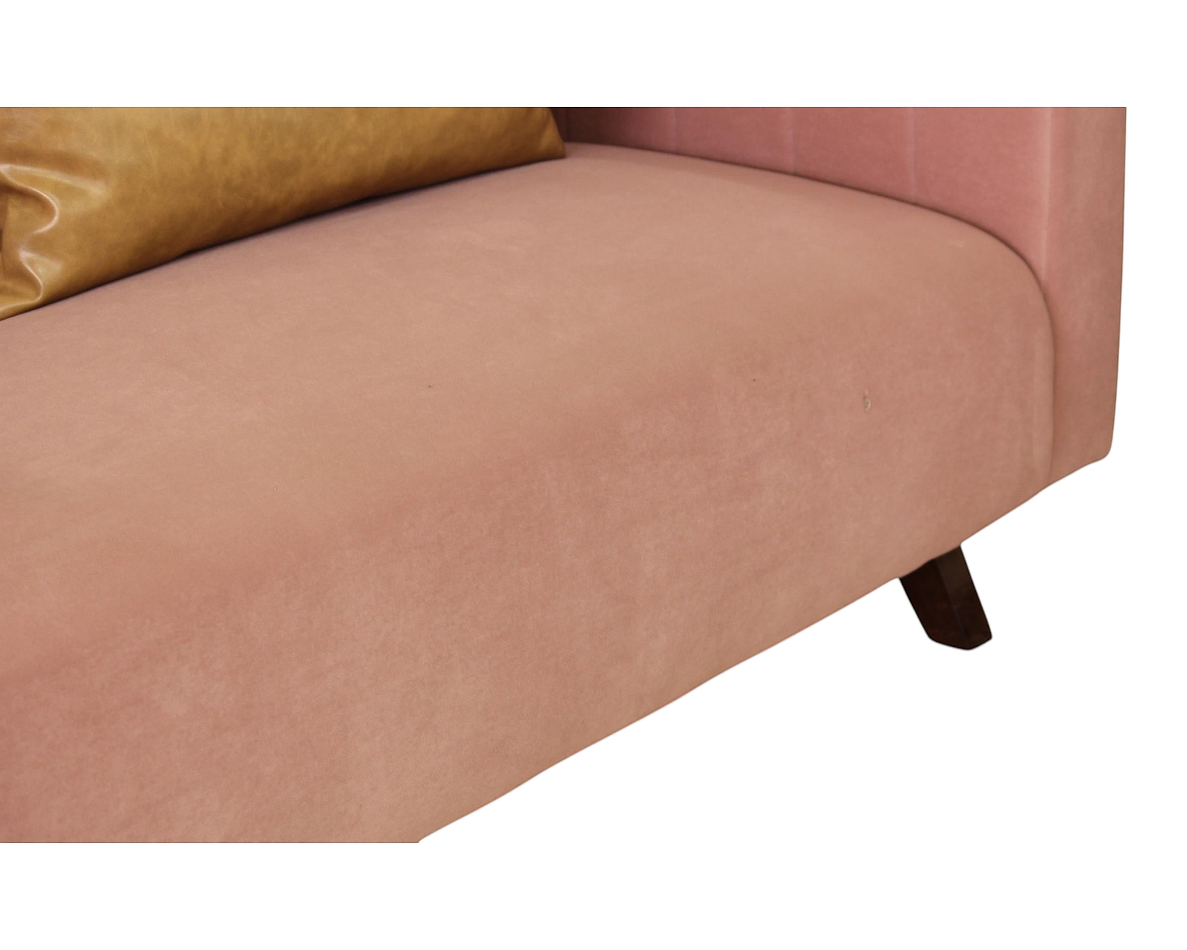 Nakoda Homes rose velvet sofa with channel tufting and faux leather accent pillow on dark wood legs.