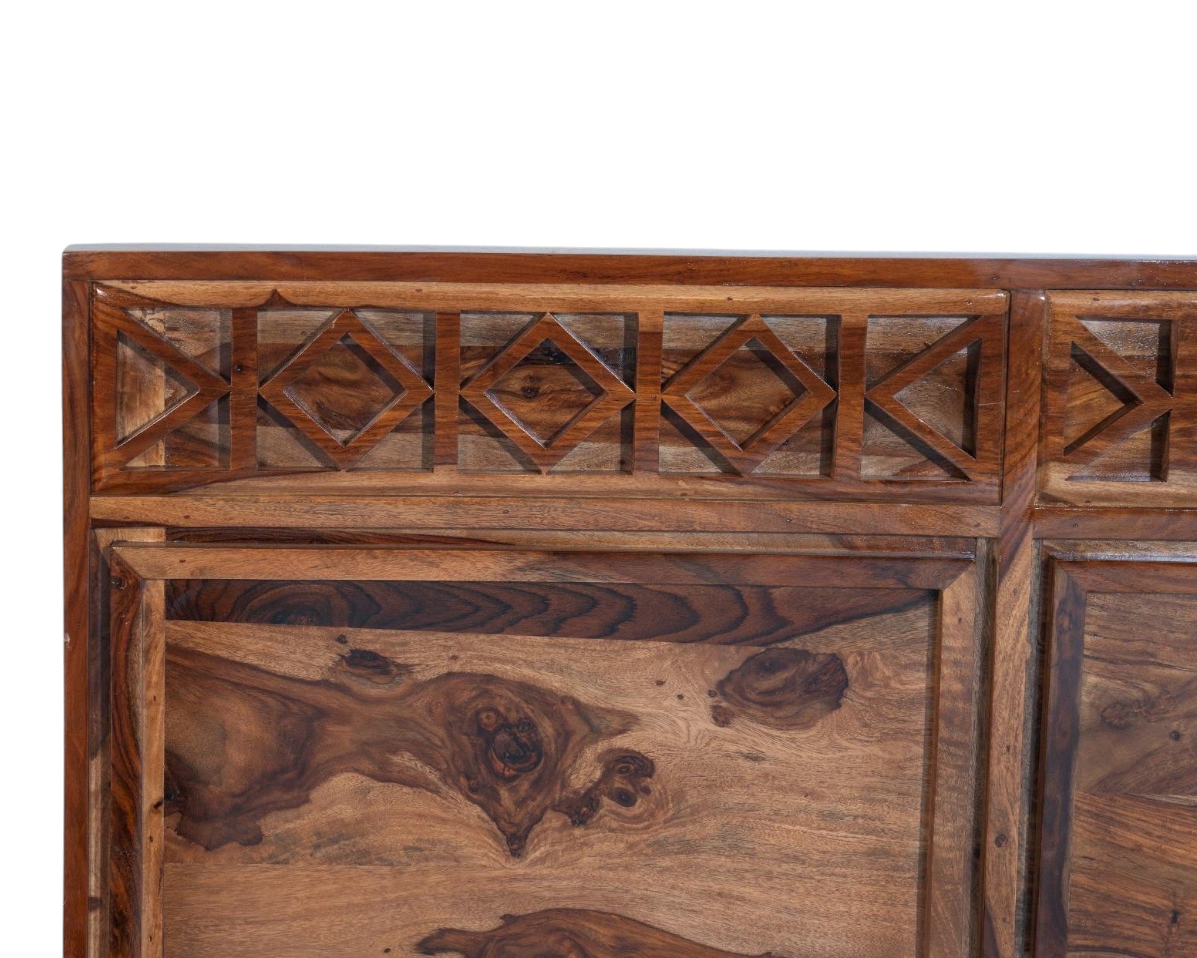 Nakoda Homes Sheesham wood bed frame with geometric carved headboard and storage drawers. Rich natural wood grain.