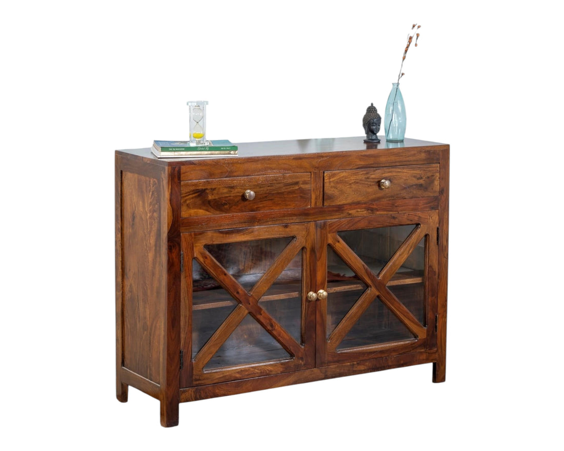 Nakoda Homes solid wood cabinet with two drawers and criss-cross glass doors, warm Sheesham wood finish.