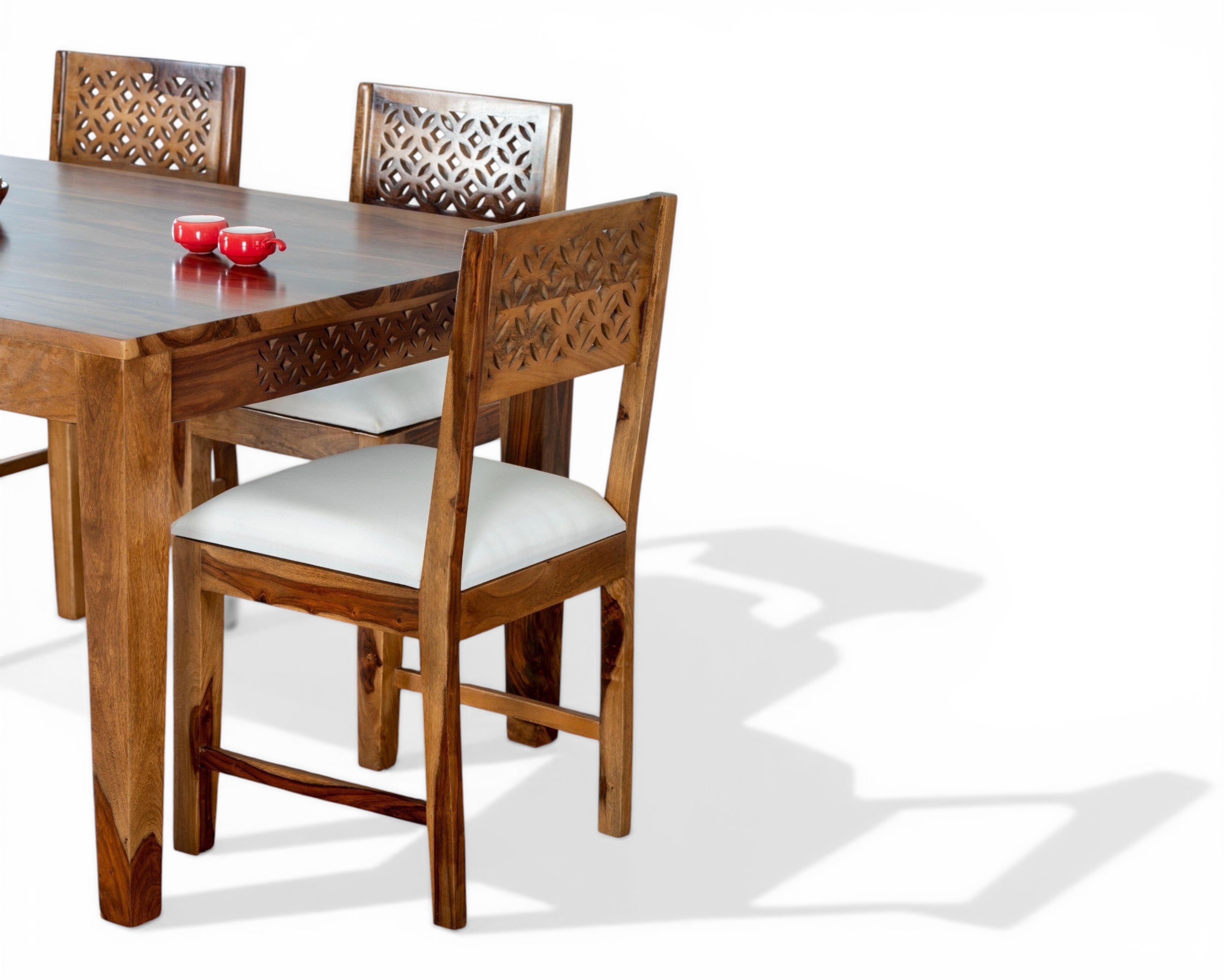 Nakoda Homes solid wood dining set with intricately carved chair backs and white cushioned seats.