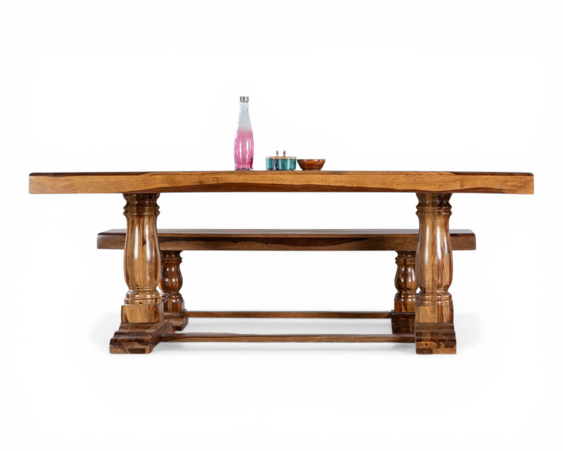 Nakoda Homes solid wood dining table with matching benches, featuring a warm-toned finish and carved pedestal legs.