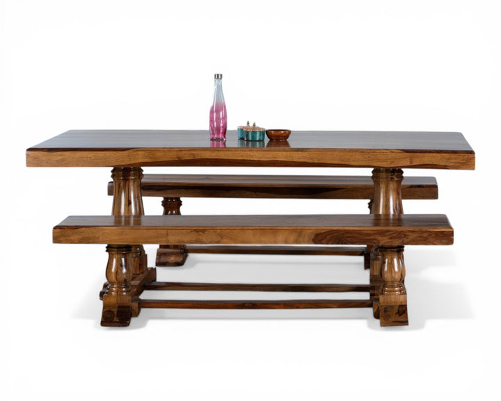 Nakoda Homes solid wood dining table with matching benches, featuring warm tones and carved pedestal legs. Rustic yet refined design.