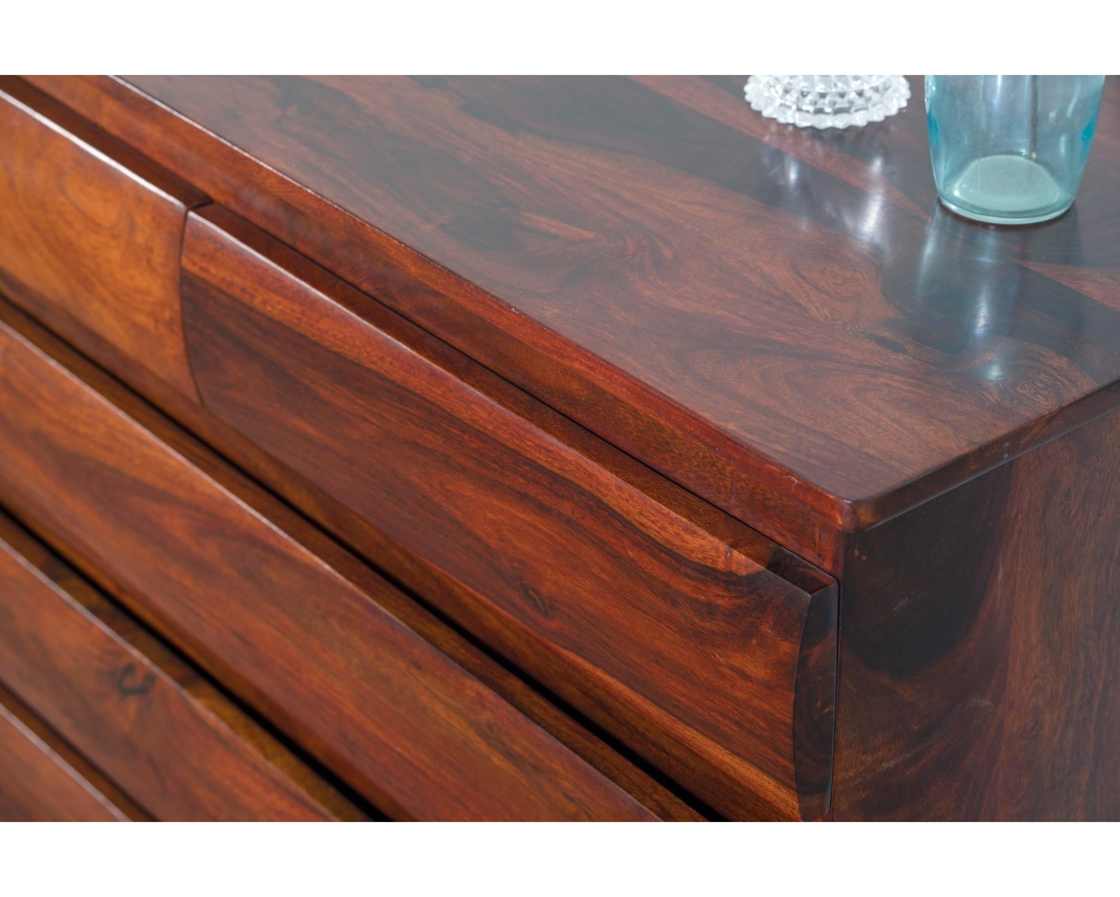 Nakoda Homes solid wood dresser in warm brown with five drawers featuring subtly curved fronts and natural wood grain.