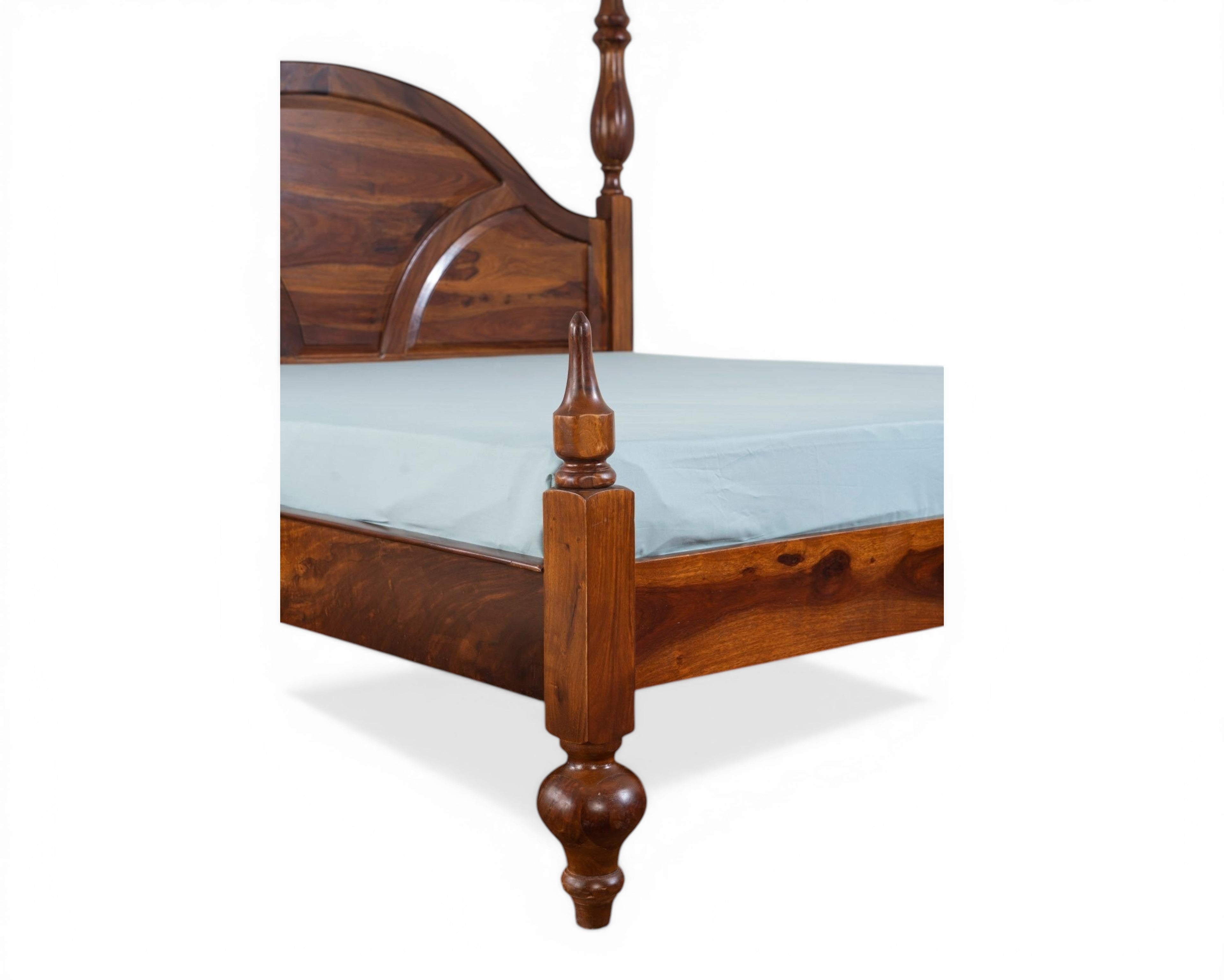 Nakoda Homes solid wood four poster canopy bed with arched headboard and ornate finials. Warm wood tone.