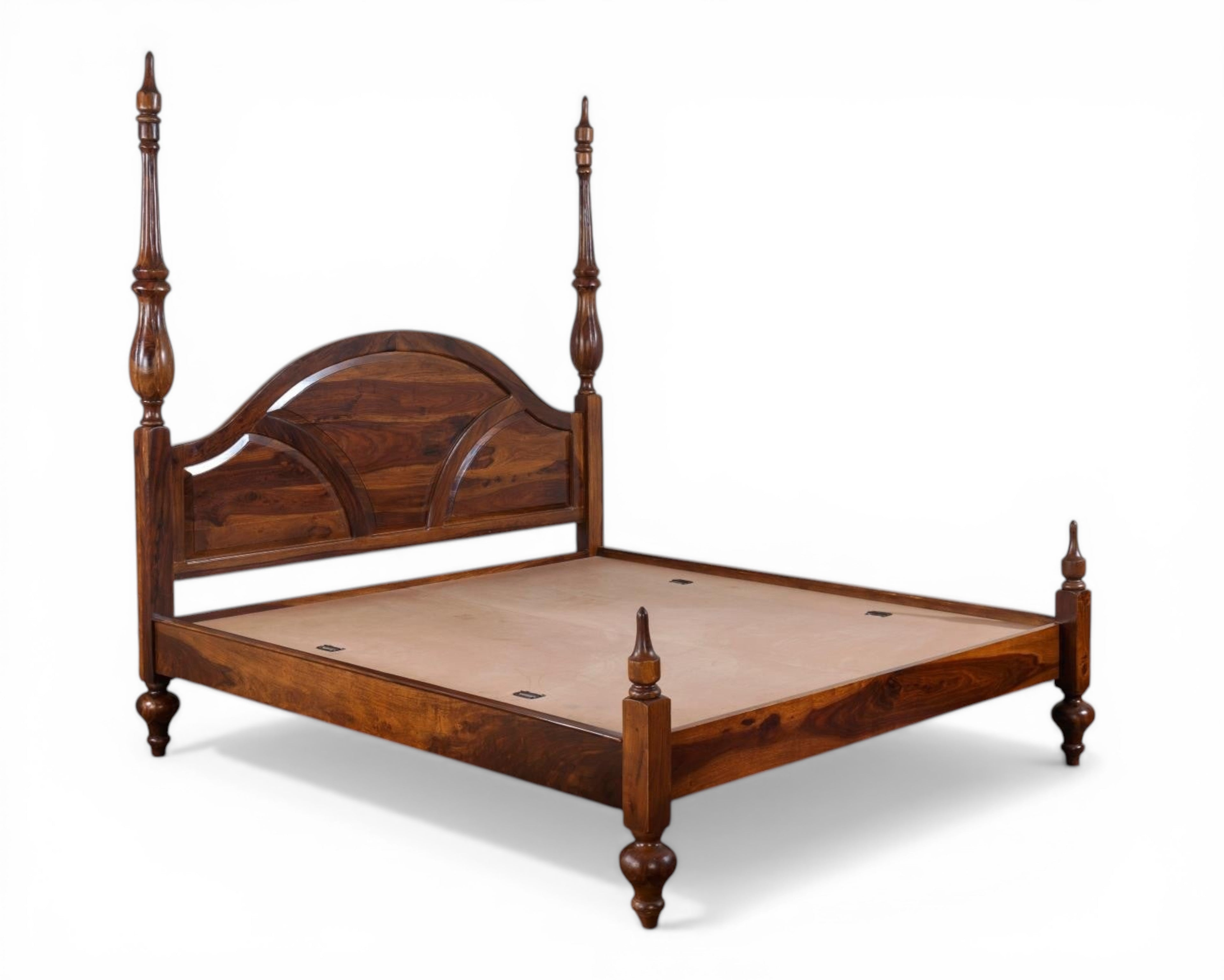 Nakoda Homes solid wood four poster canopy bed with arched headboard and intricate detailing. Warm wood tone.