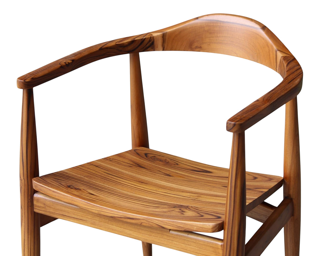Nakoda Homes teak wood dining chair with curved back and armrests, natural wood grain finish.