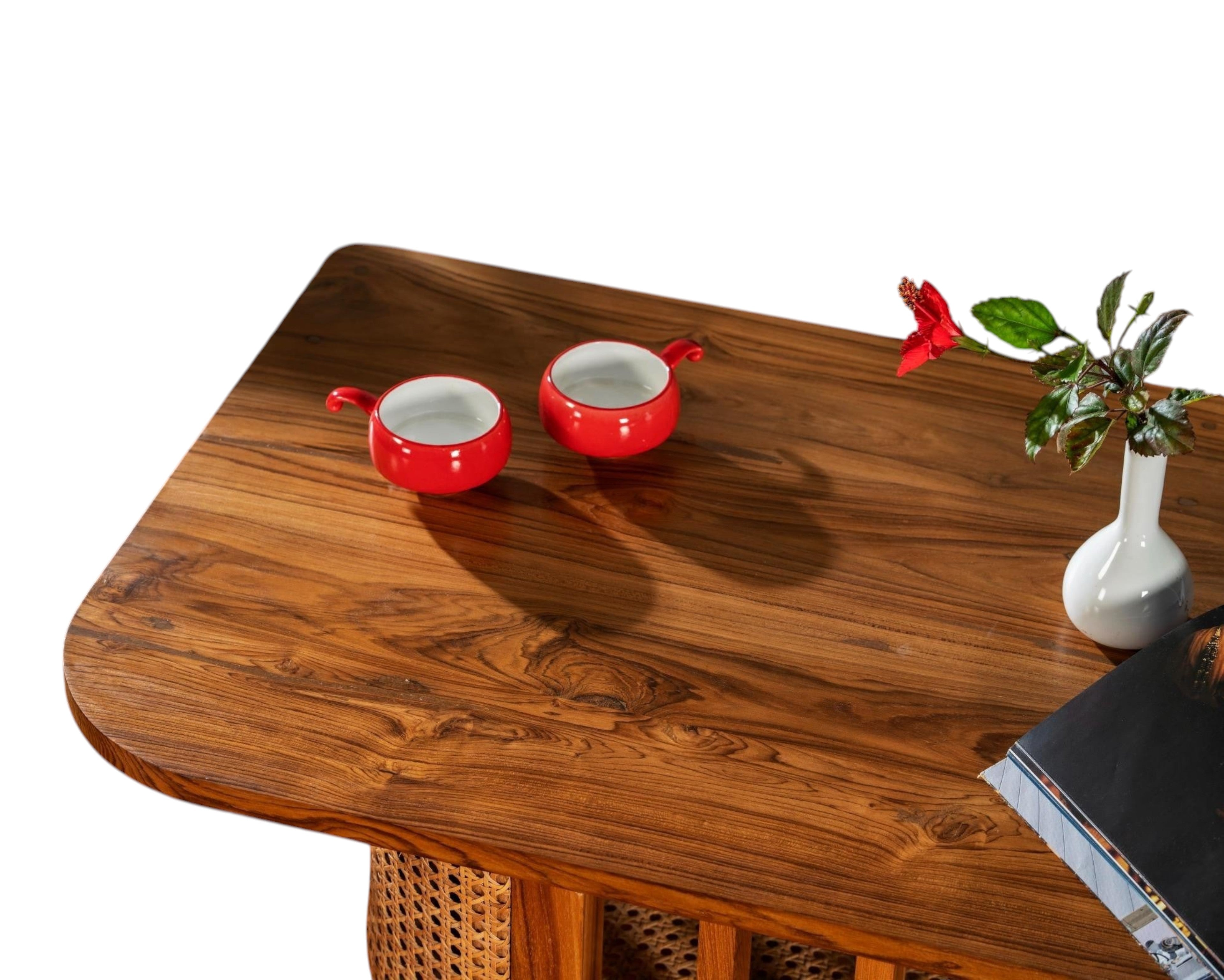 Nakoda Homes natural wood coffee table with cane detailing and a red hibiscus flower in a white vase.