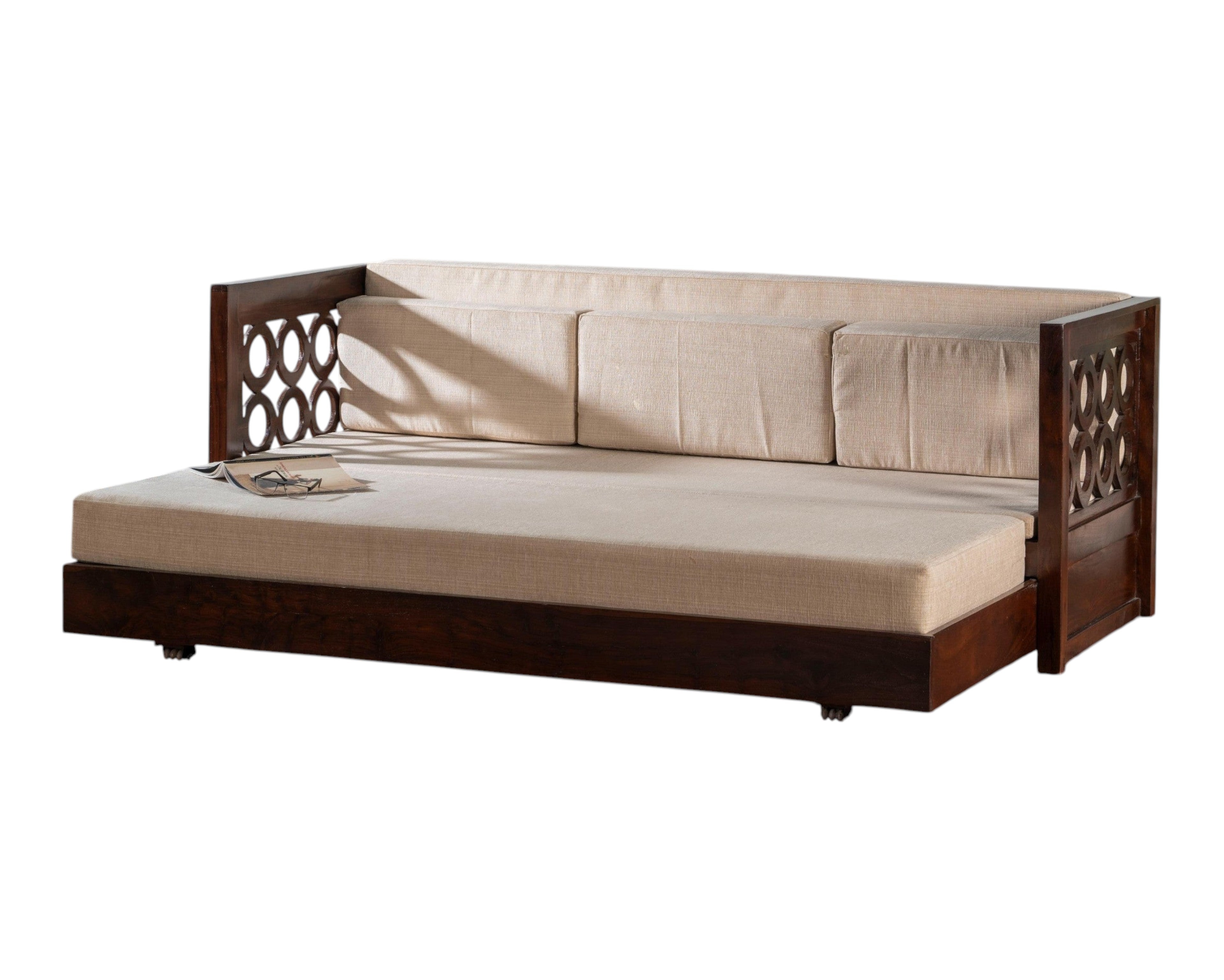 Nakoda Homes dark wood daybed with neutral upholstered seat and intricate circular armrest detailing. Converts to a bed.
