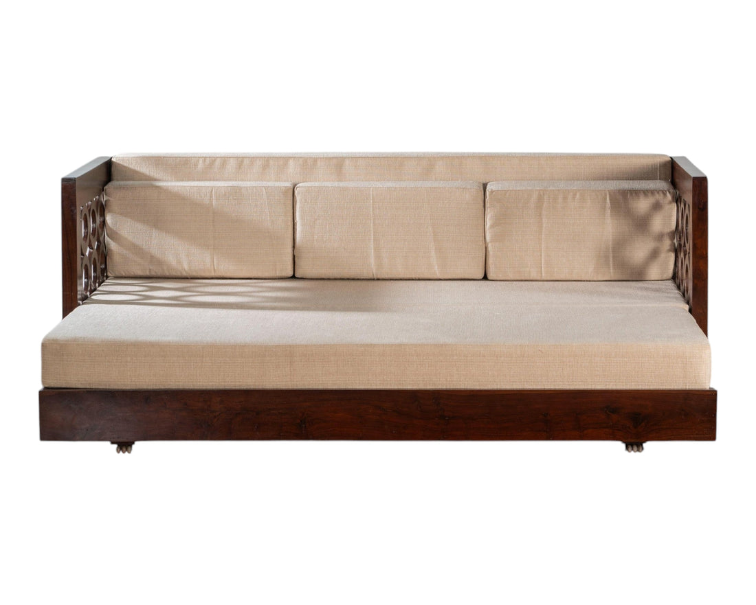 Nakoda Homes dark wood daybed with neutral upholstered seat and intricate circular armrest detailing.
