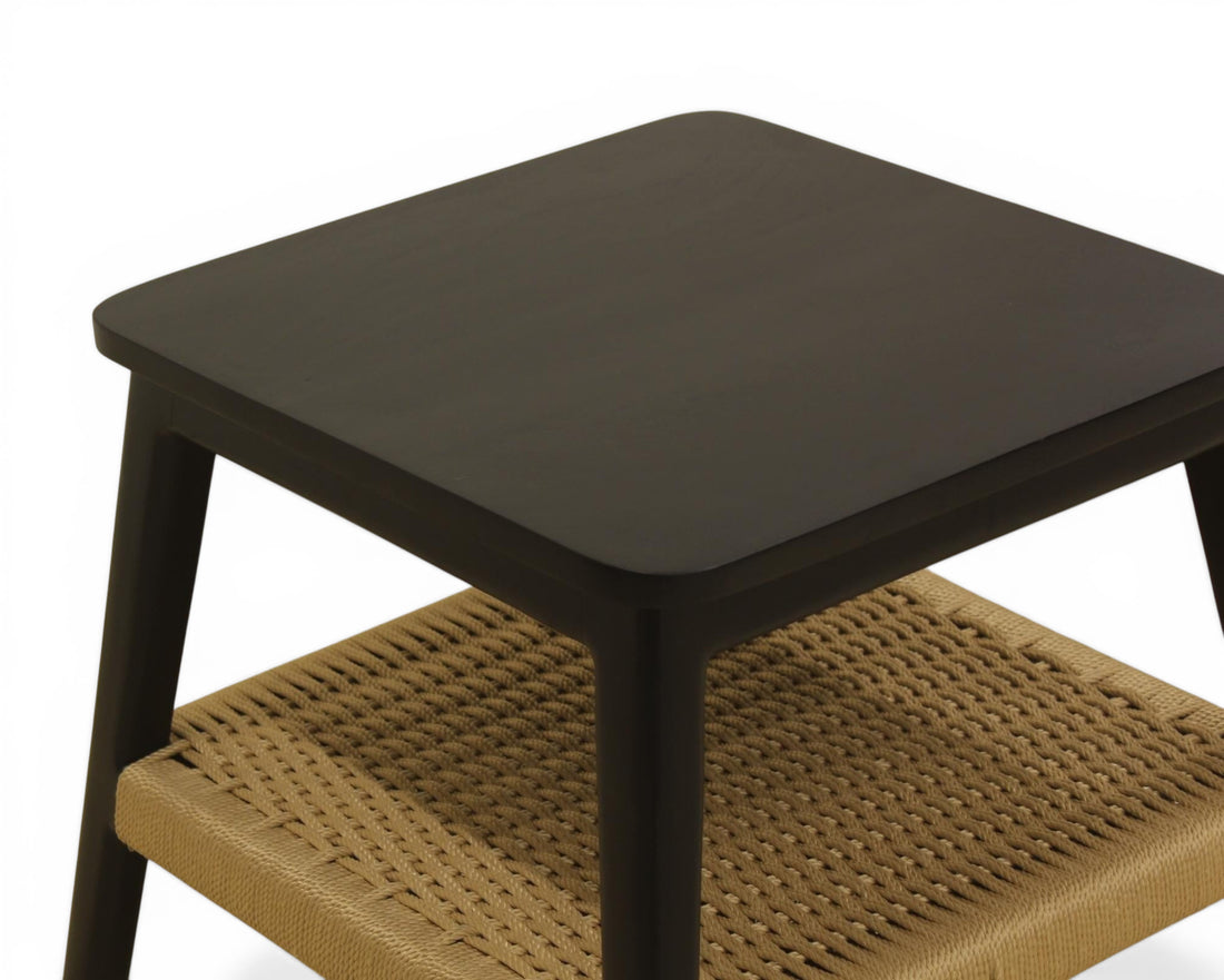 Nakoda Homes black wooden side table with natural woven rattan shelf, modern design.