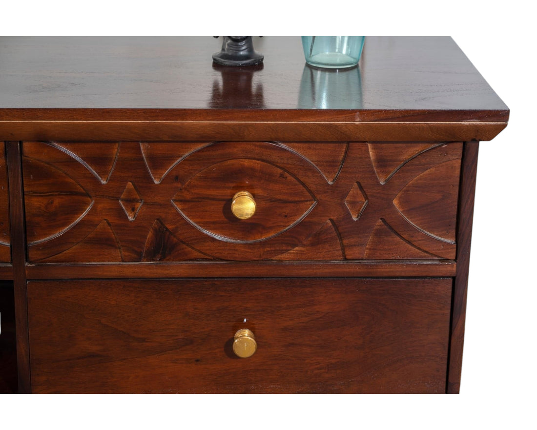 Nakoda Homes dark wood media console with carved geometric drawer fronts and brass hardware.