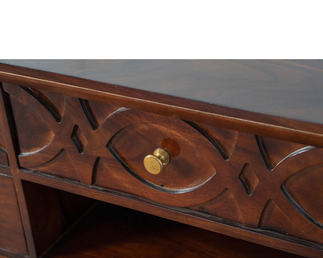 Nakoda Homes dark wood media console with carved geometric drawer fronts and brass hardware.