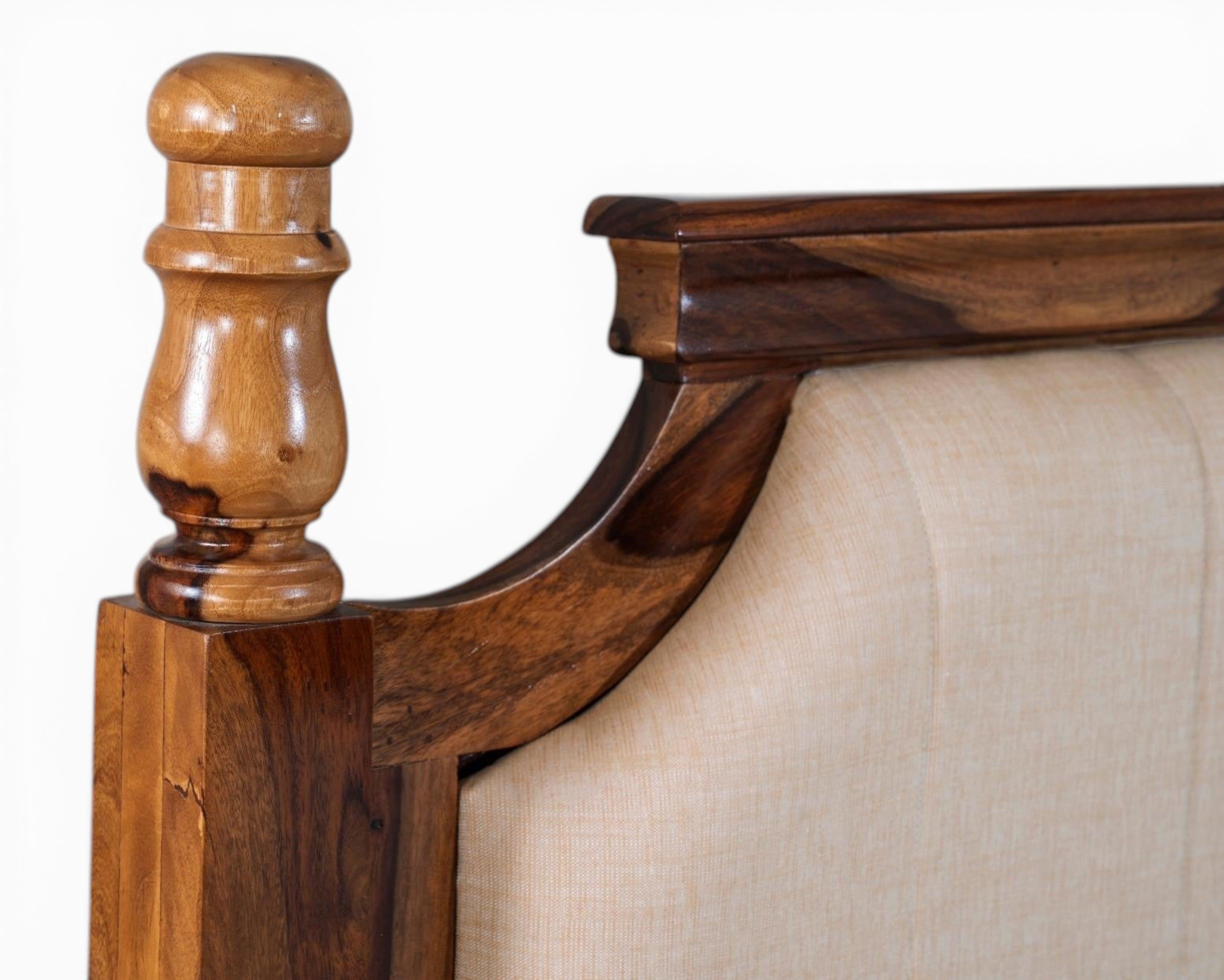 Nakoda Homes classic wooden bed frame with beige upholstered headboard and decorative wood post.