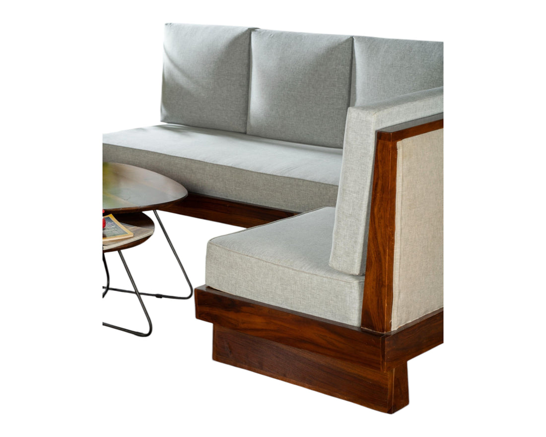 Nakoda Homes modern three-seater sofa with light grey upholstered cushions and a rich-toned wooden frame. Clean lines and minimalist design.