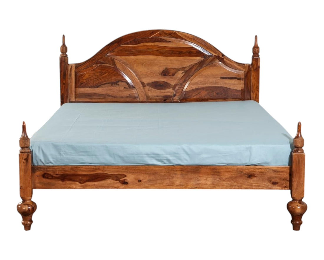 Nakoda Homes ornate Sheesham wood bed frame with arched headboard, intricate carvings, and turned posts. Classic design.