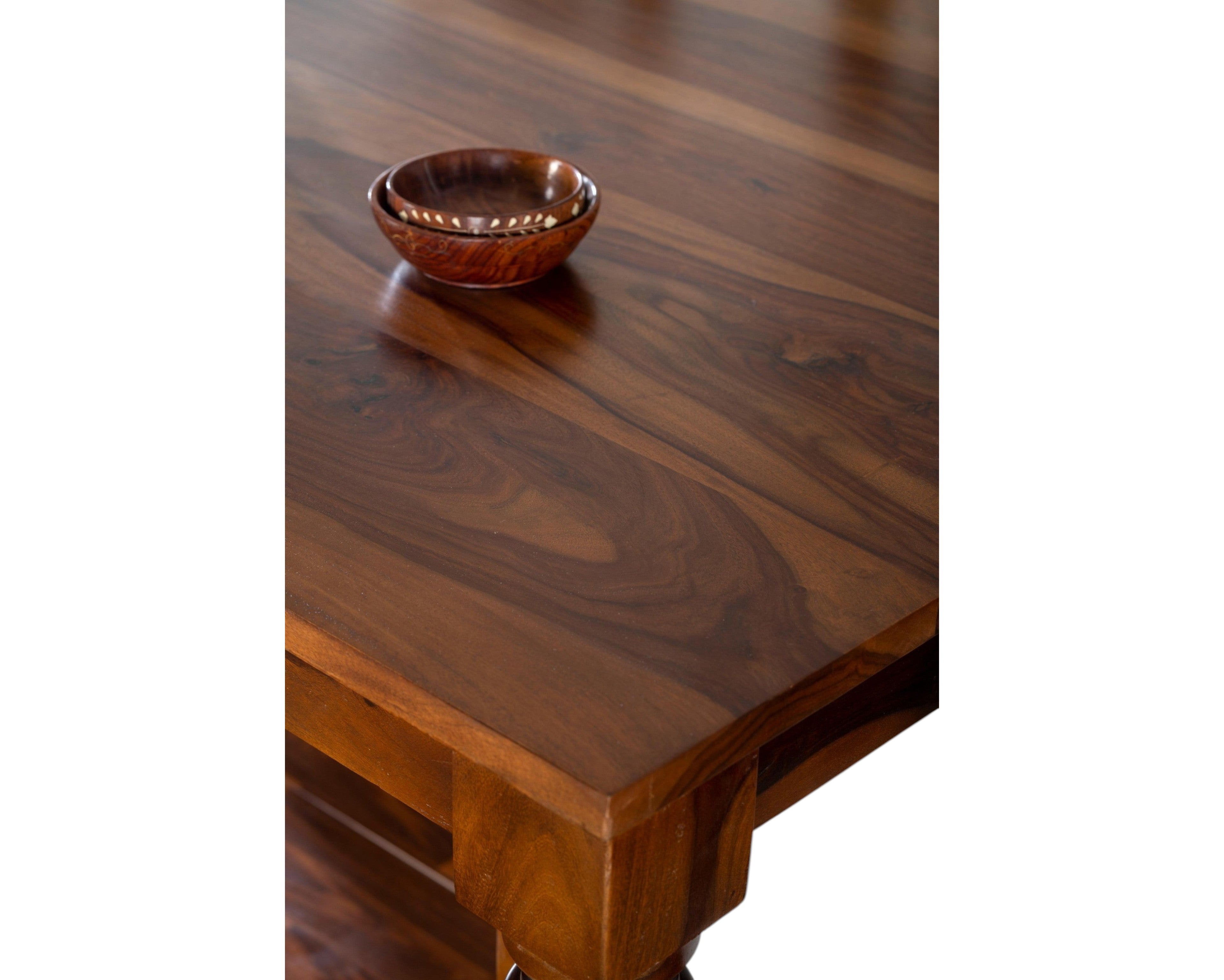 Nakoda Homes Sheesham wood dining table with carved legs and upholstered seats. Rich wood finish.