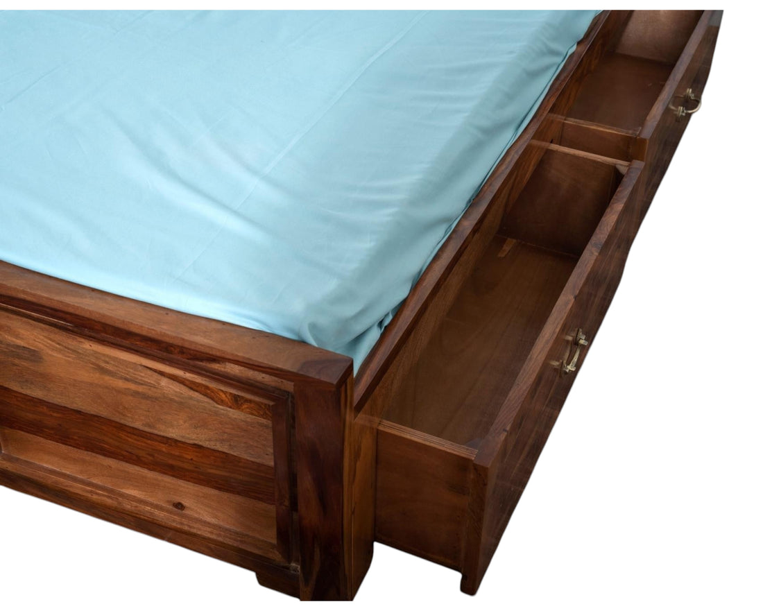 Nakoda Homes Sheesham wood bed frame with built-in storage drawers and carved headboard. Natural wood grain.
