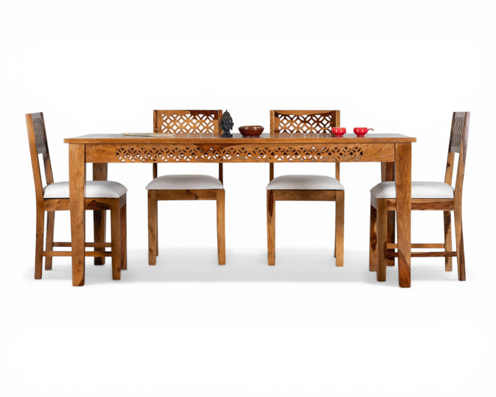 Nakoda Homes solid wood dining set with intricately carved details and white cushioned seats. Includes a rectangular table and four chairs.