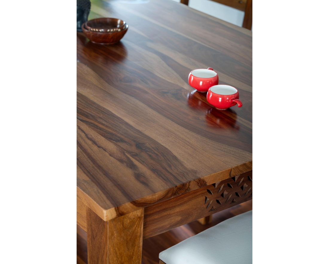 Nakoda Homes solid wood dining set with intricate carvings on chair backs and tabletop. Natural wood finish.